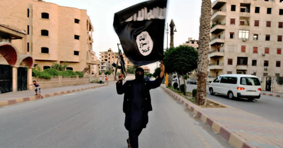 Persona levantando un arma y la bandera del Estado Islámico